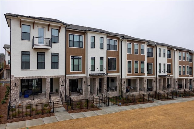 townhome / multi-family property with brick siding, fence, and a residential view