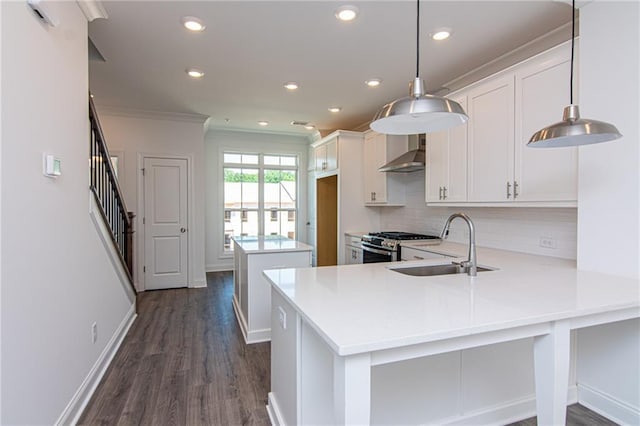 kitchen with wall chimney exhaust hood, stainless steel gas range, light countertops, crown molding, and a sink