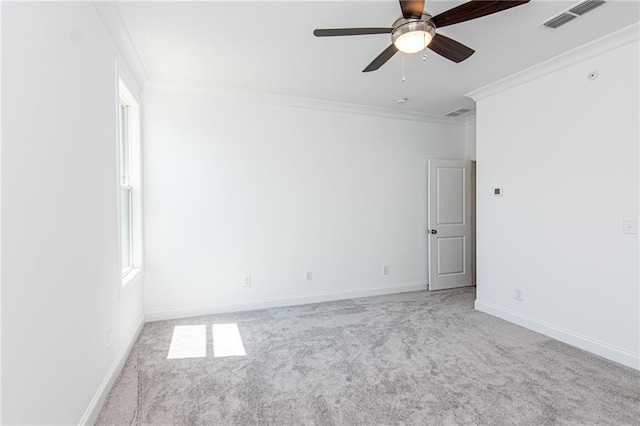 spare room with light colored carpet, visible vents, ornamental molding, ceiling fan, and baseboards