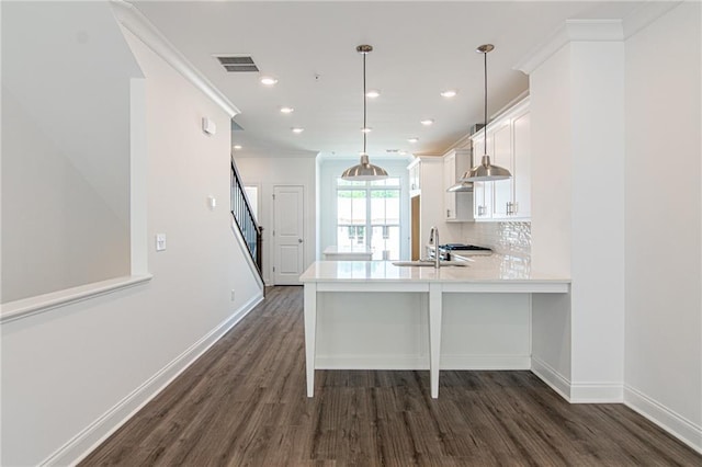 kitchen featuring a sink, visible vents, white cabinets, decorative backsplash, and crown molding