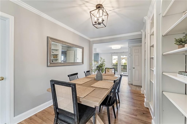 dining area featuring baseboards, wood finished floors, crown molding, french doors, and a notable chandelier