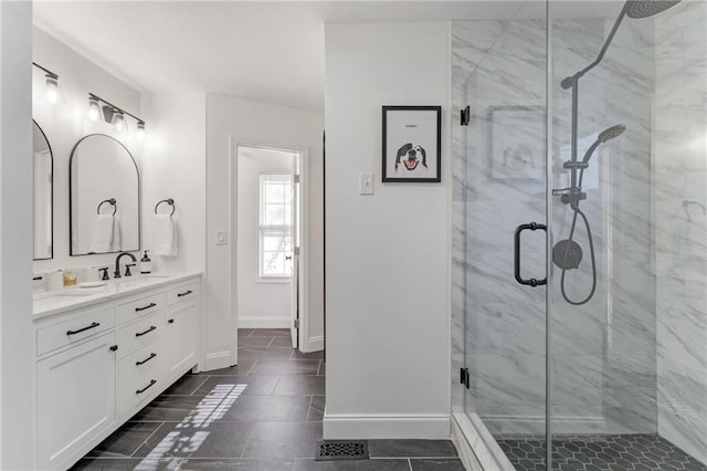 bathroom with a marble finish shower, baseboards, and vanity