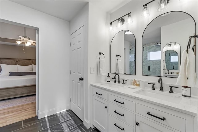 ensuite bathroom featuring ceiling fan, connected bathroom, an enclosed shower, and a sink