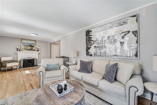 living area with baseboards, a fireplace, wood finished floors, and crown molding