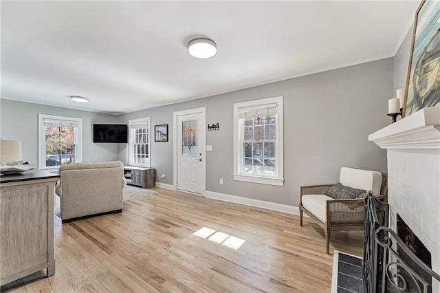 living area with light wood-style floors, baseboards, and a fireplace with flush hearth