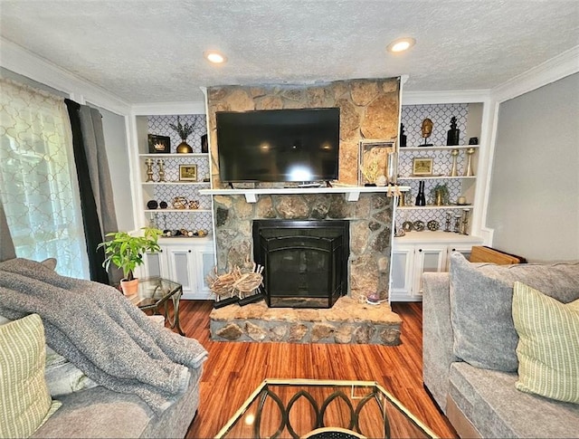 living room with built in features, hardwood / wood-style flooring, a fireplace, and ornamental molding