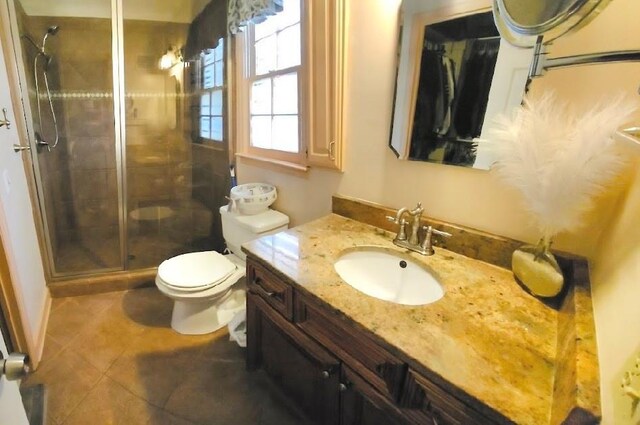 bathroom featuring vanity, toilet, tile patterned floors, and a shower with door