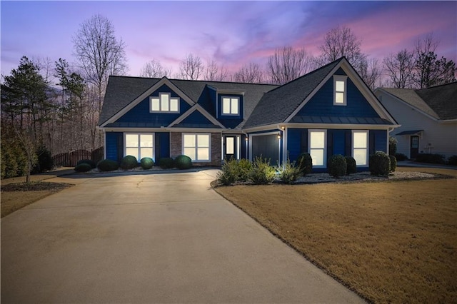 view of front facade featuring concrete driveway, an attached garage, a front yard, a standing seam roof, and metal roof