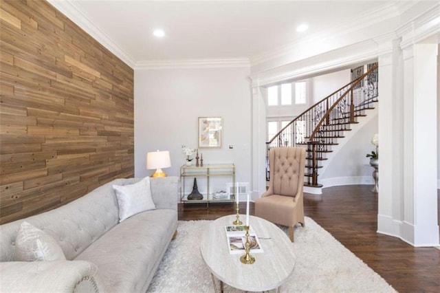 living area featuring wooden walls, stairway, crown molding, baseboards, and dark wood-type flooring