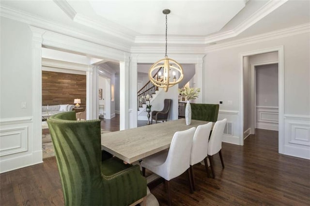 dining room featuring a chandelier, a decorative wall, dark wood-style floors, crown molding, and a wainscoted wall