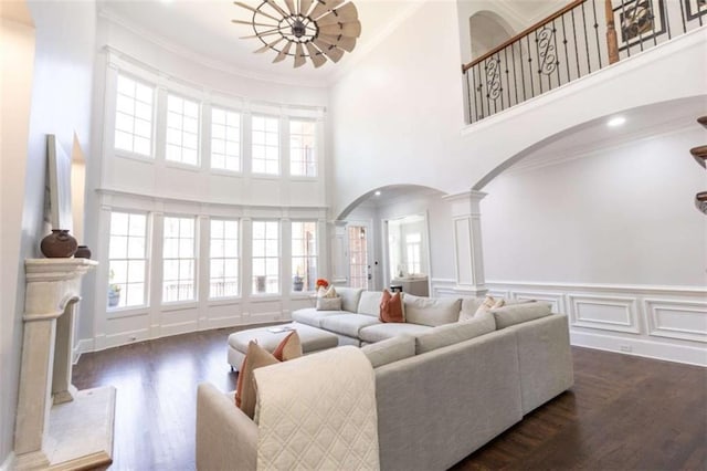 living area with arched walkways, ornate columns, a high ceiling, plenty of natural light, and a chandelier