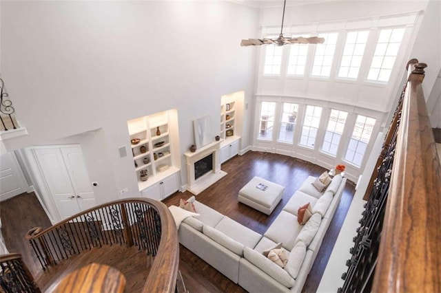 living room with a high ceiling, wood finished floors, a premium fireplace, baseboards, and ornamental molding