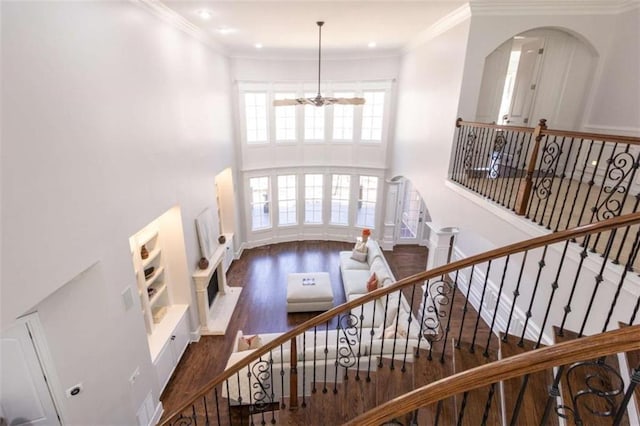 foyer with wood finished floors, a chandelier, a high ceiling, ornamental molding, and arched walkways