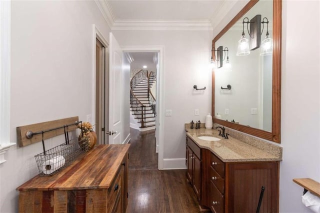 bathroom with wood finished floors, ornamental molding, vanity, and baseboards