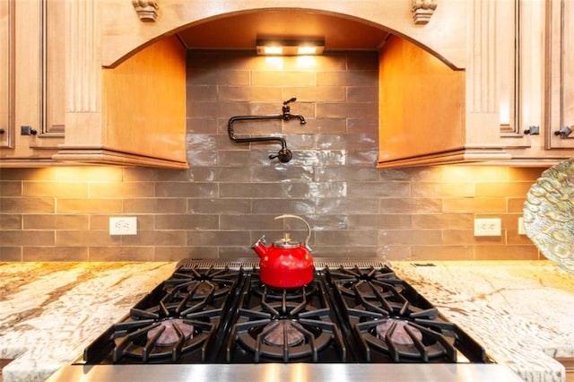 kitchen featuring tasteful backsplash, arched walkways, and gas cooktop