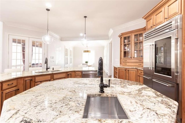 kitchen featuring appliances with stainless steel finishes, a sink, ornamental molding, and brown cabinets
