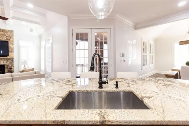 kitchen with a sink, open floor plan, pendant lighting, light stone countertops, and a fireplace