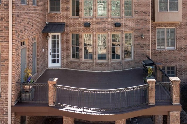 view of side of home featuring brick siding and a wooden deck
