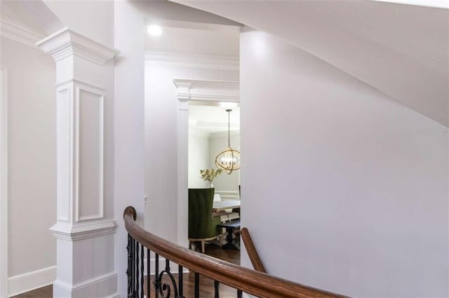 hallway featuring ornamental molding, baseboards, an upstairs landing, wood finished floors, and a chandelier