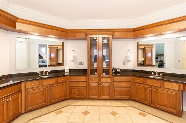 ensuite bathroom with ornamental molding, inlaid floor details, double vanity, and tile patterned flooring