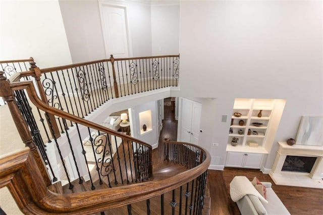 staircase with wood finished floors, baseboards, and a towering ceiling