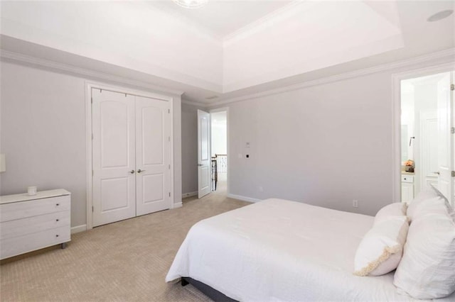 bedroom featuring a tray ceiling, light carpet, ornamental molding, a closet, and baseboards