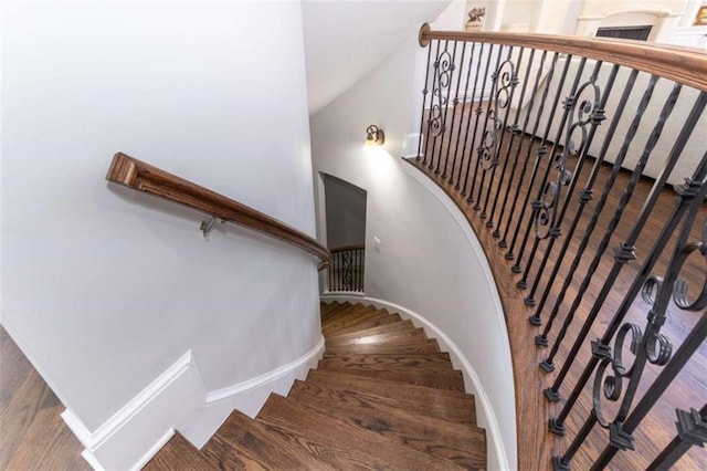 stairway with high vaulted ceiling, baseboards, and wood finished floors