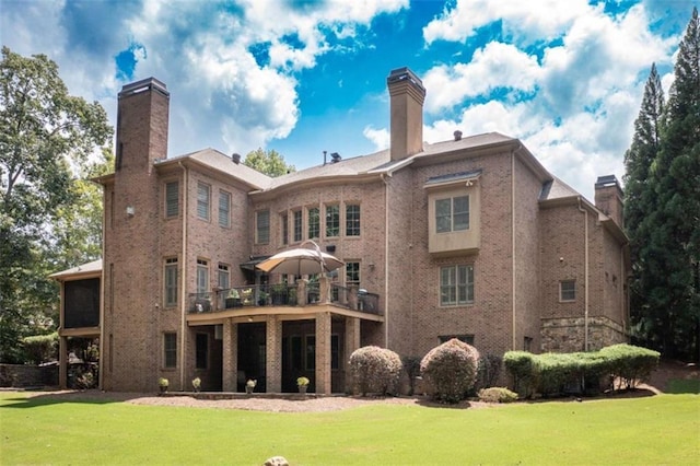 back of house featuring a chimney, a yard, and brick siding