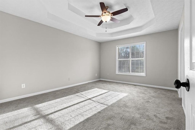 carpeted spare room featuring ceiling fan and a tray ceiling