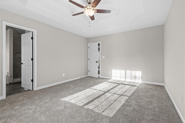 unfurnished room with ceiling fan, a raised ceiling, and carpet floors