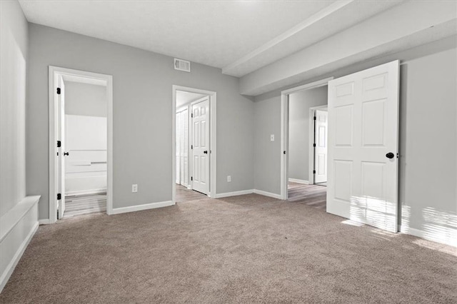 unfurnished bedroom with ensuite bathroom and carpet floors