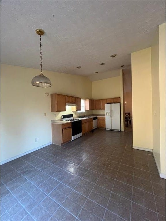 kitchen with white appliances, decorative light fixtures, and lofted ceiling