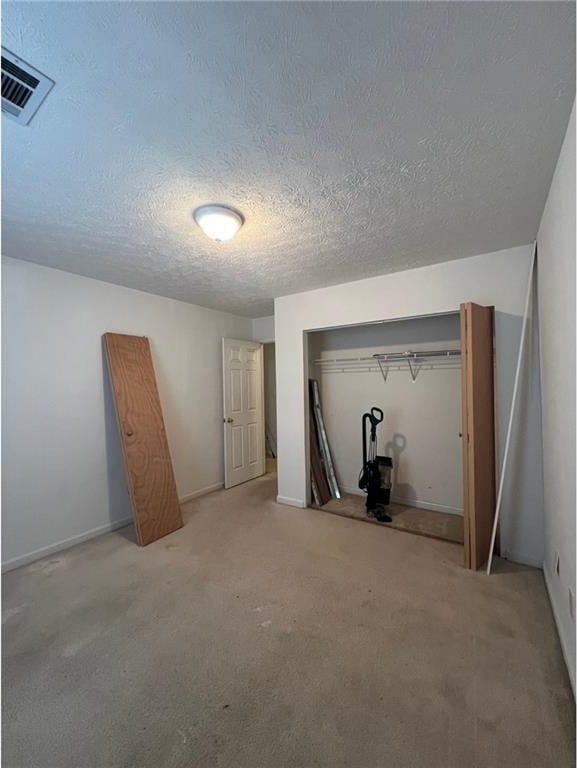 unfurnished bedroom with carpet, a textured ceiling, and a closet