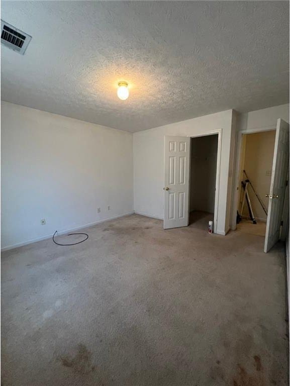 spare room featuring a textured ceiling and light carpet