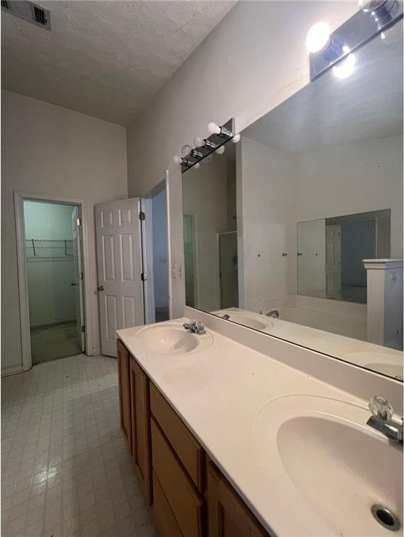 bathroom featuring vanity, a textured ceiling, and walk in shower