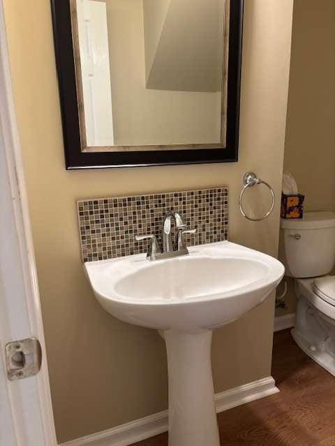 1629 Marsanne Ter, Kennesaw, GA 30152 - half bathroom featuring toilet, baseboards, wood finished floors, decorative backsplash, and a sink