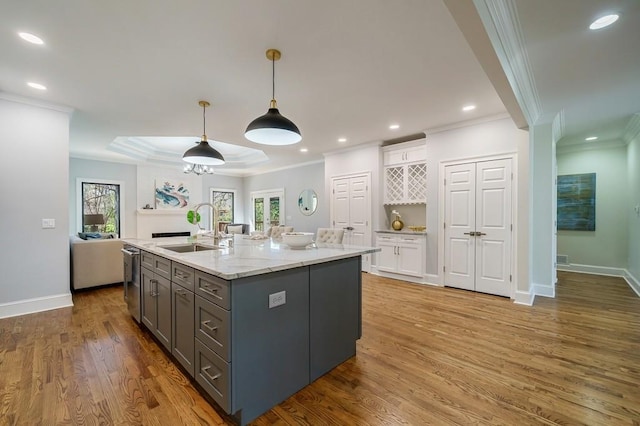 kitchen with white cabinetry, sink, stainless steel dishwasher, an island with sink, and pendant lighting