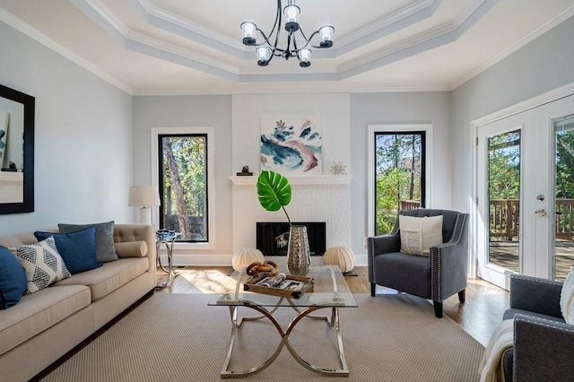 living room with ornamental molding, a tray ceiling, a healthy amount of sunlight, and light hardwood / wood-style floors