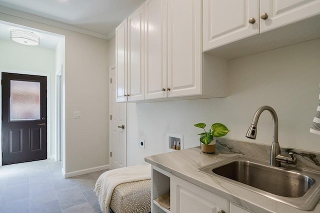 kitchen with white cabinetry, sink, and ornamental molding