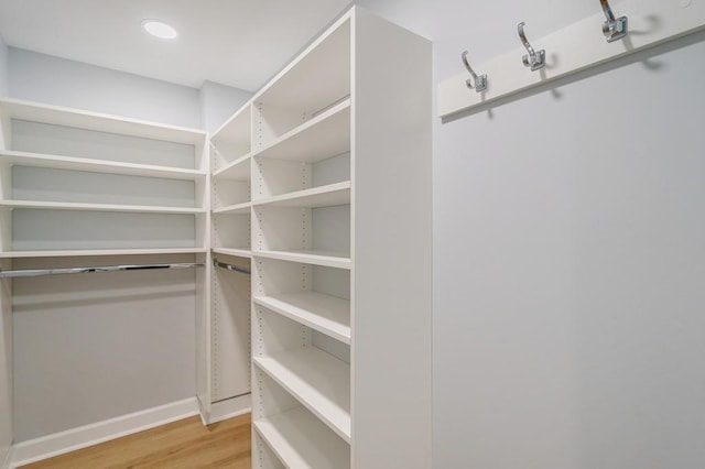 walk in closet with light hardwood / wood-style flooring