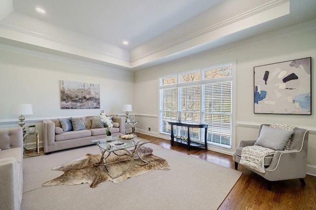 living room with dark hardwood / wood-style flooring, a raised ceiling, and ornamental molding