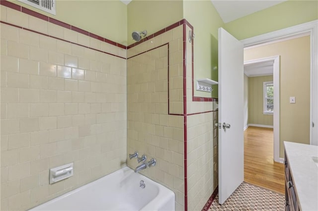 bathroom featuring wood-type flooring, tiled shower / bath, and vanity