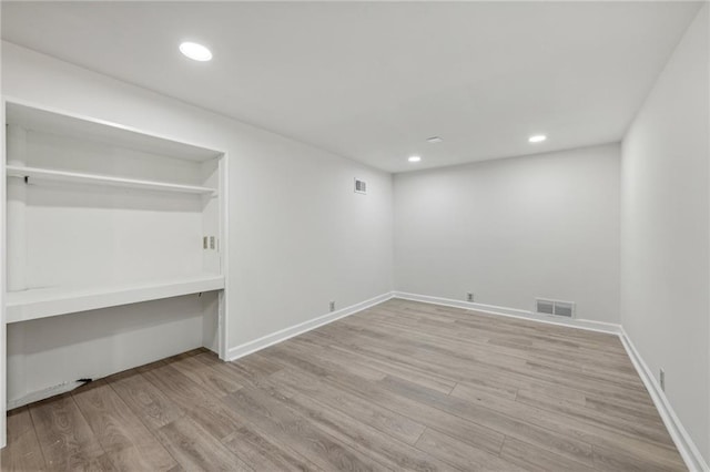 interior space with light wood-type flooring, built in desk, and a closet