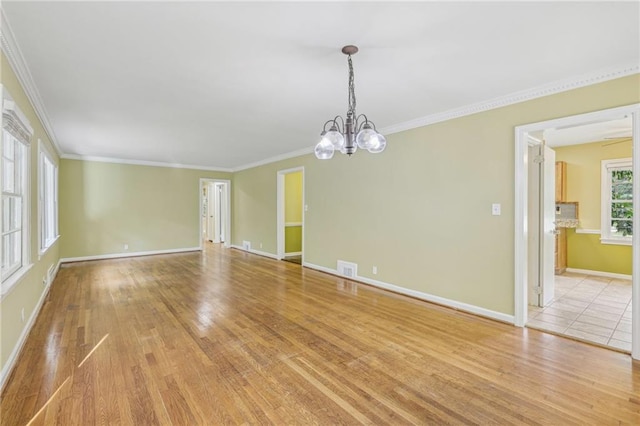 unfurnished room featuring light wood-type flooring, crown molding, and a chandelier