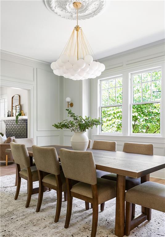 dining area with ornamental molding, light wood-style flooring, and a decorative wall