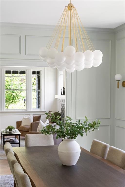 dining space featuring crown molding, light wood-style floors, and a decorative wall