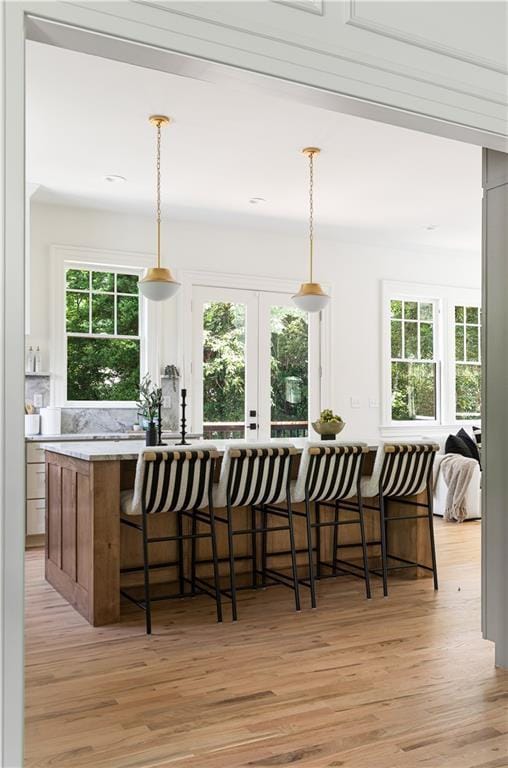 kitchen with light wood-style floors, a wealth of natural light, and a kitchen breakfast bar