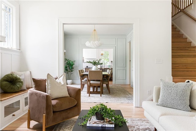 living room with stairway, light wood-style flooring, and a decorative wall