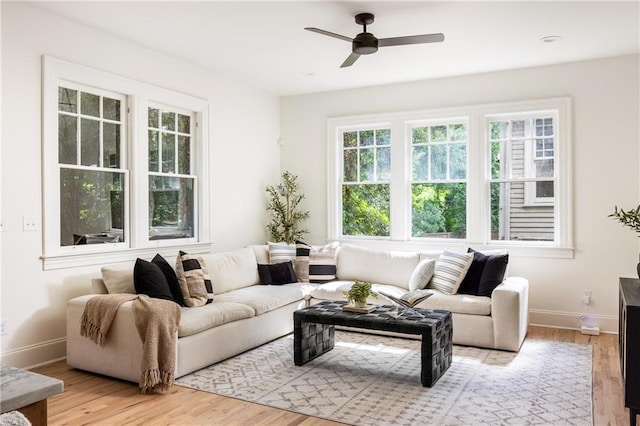 living room featuring a ceiling fan, baseboards, and wood finished floors