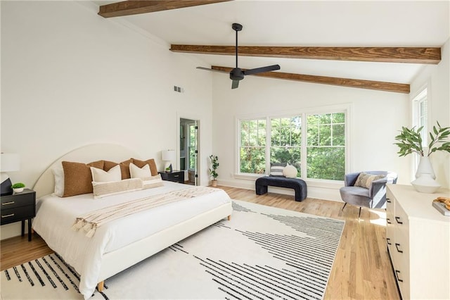 bedroom featuring multiple windows, beam ceiling, and light wood-style floors